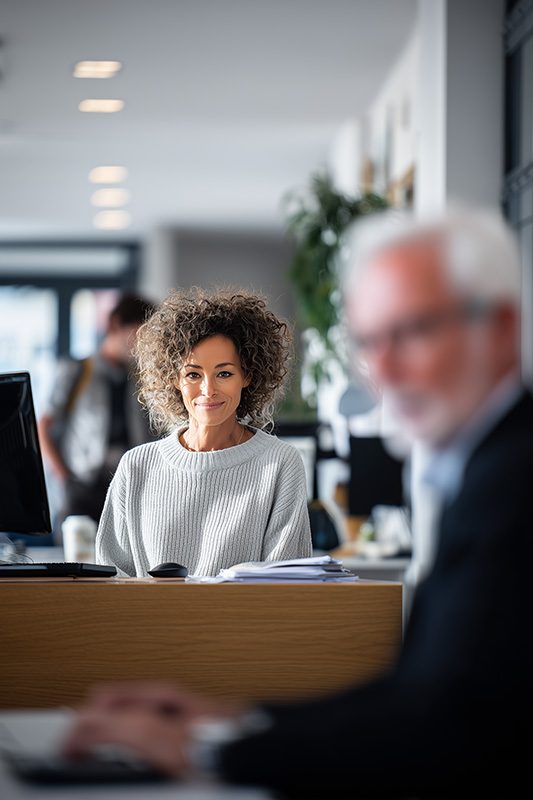 Femme souriante assise à son bureau dans un espace de travail moderne.