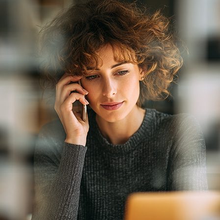 Professionnelle en communication téléphonique devant son ordinateur.